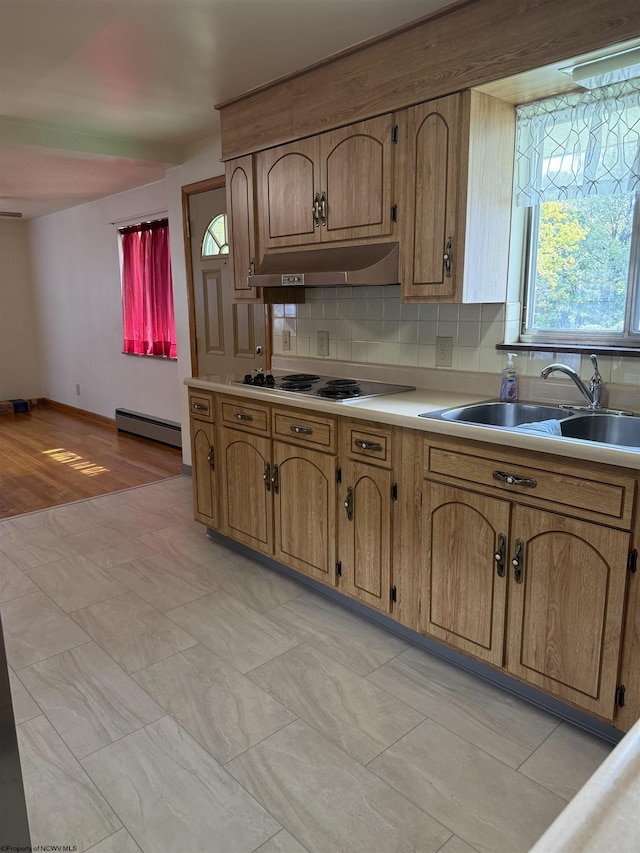 kitchen with sink, cooktop, baseboard heating, light hardwood / wood-style floors, and decorative backsplash