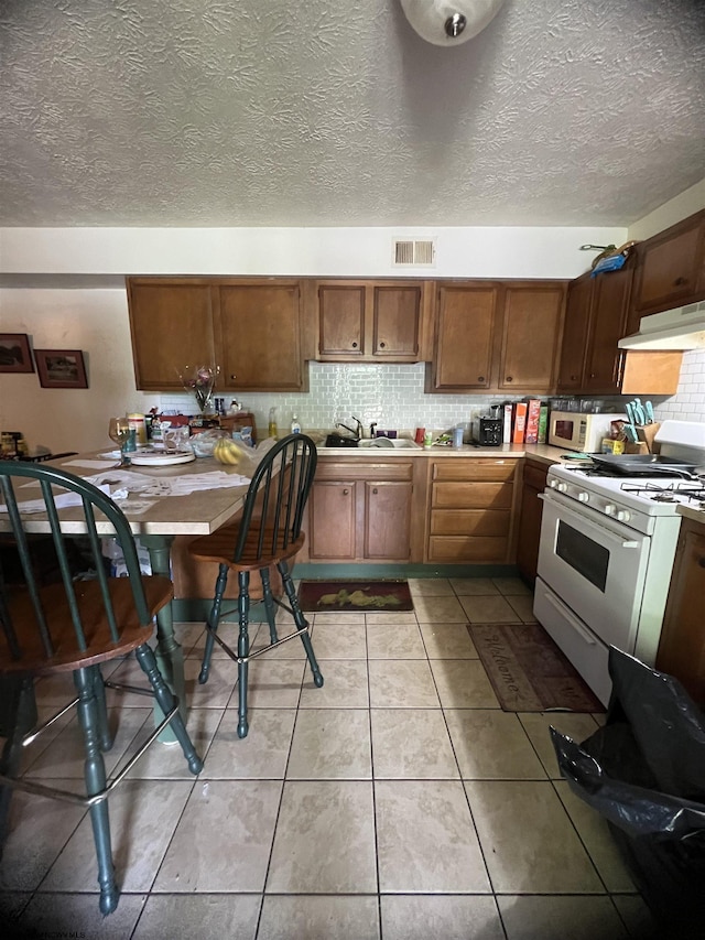 kitchen featuring a textured ceiling, sink, light tile patterned flooring, and white appliances