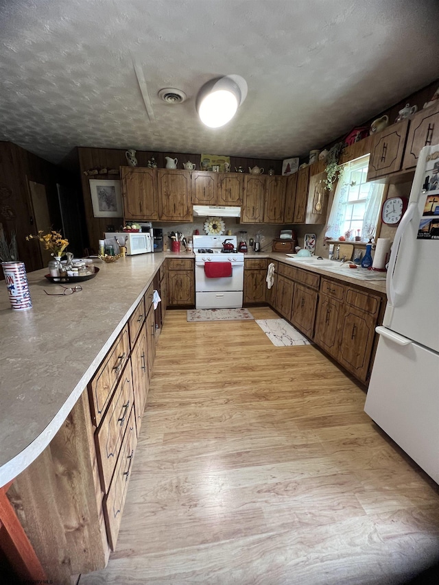 kitchen featuring sink, white appliances, a textured ceiling, and light hardwood / wood-style flooring