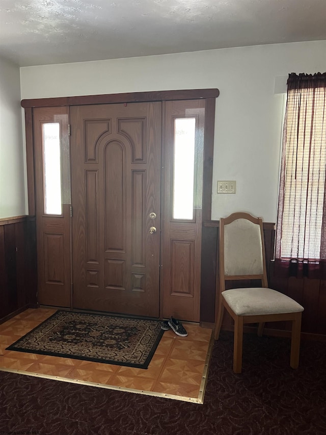 entrance foyer with parquet flooring, plenty of natural light, and wooden walls