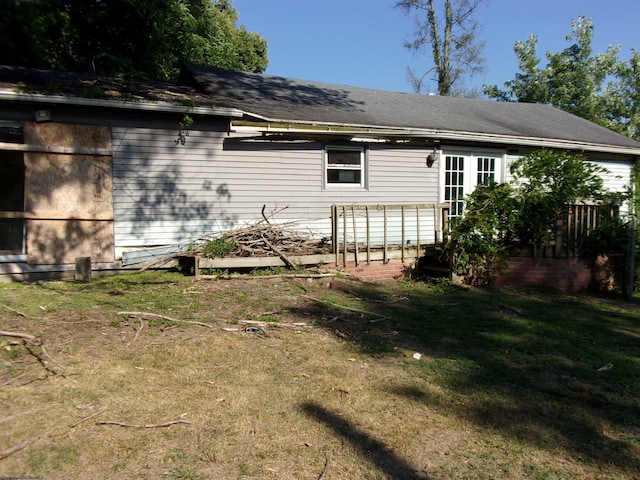 rear view of house featuring a wooden deck and a lawn