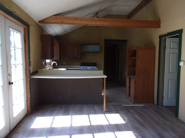 kitchen with lofted ceiling, hardwood / wood-style flooring, stove, kitchen peninsula, and french doors