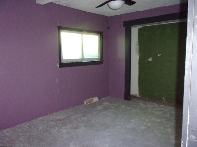 carpeted spare room featuring a textured ceiling and ceiling fan