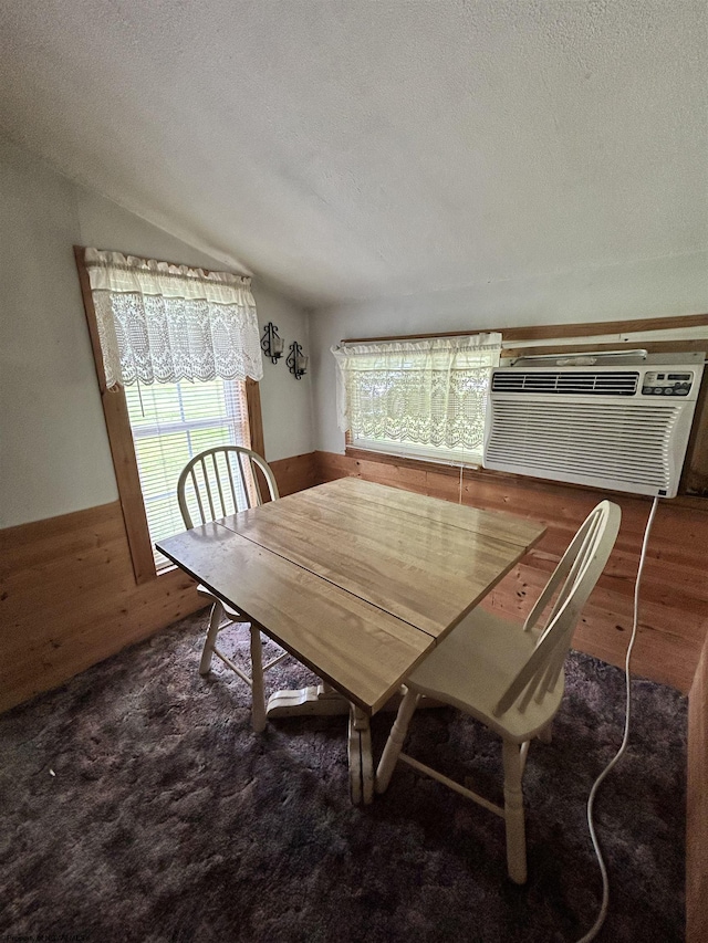 carpeted dining area featuring vaulted ceiling, a wall unit AC, a textured ceiling, and wood walls