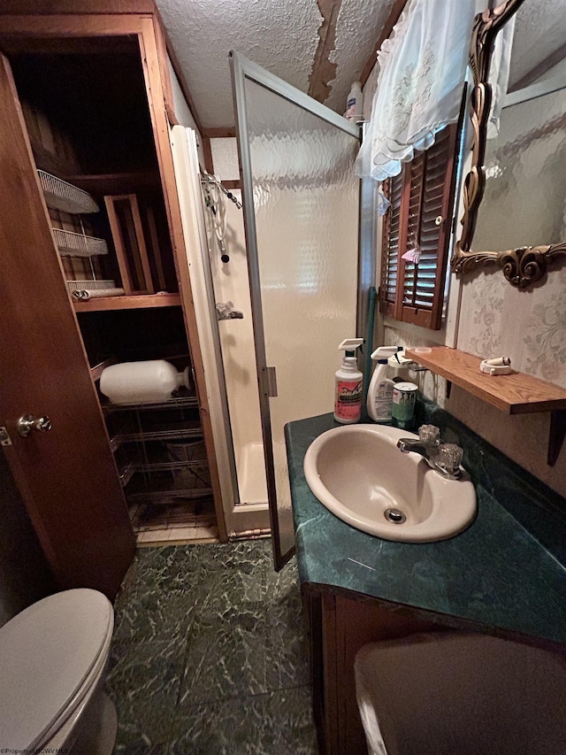 bathroom with walk in shower, vanity, toilet, and a textured ceiling