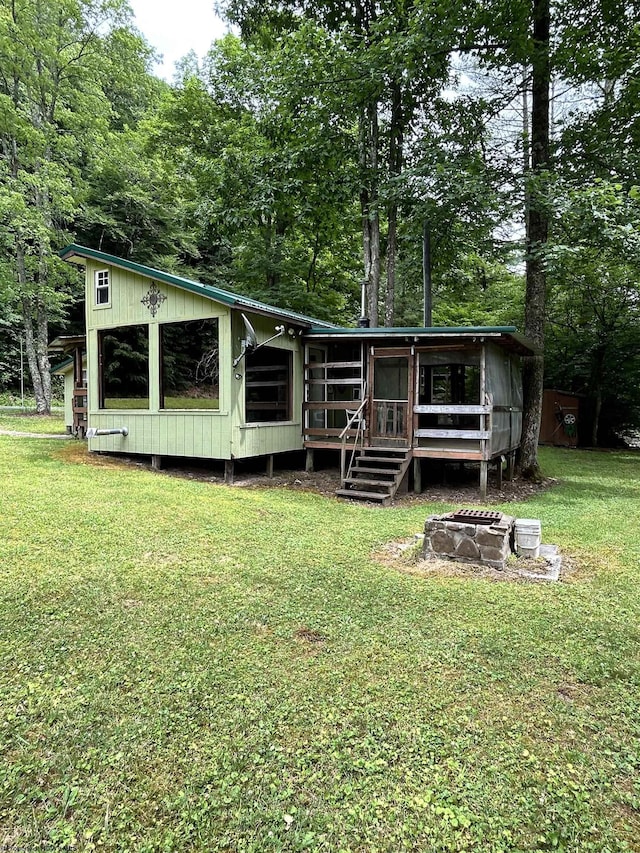 back of property featuring an outdoor fire pit and a yard