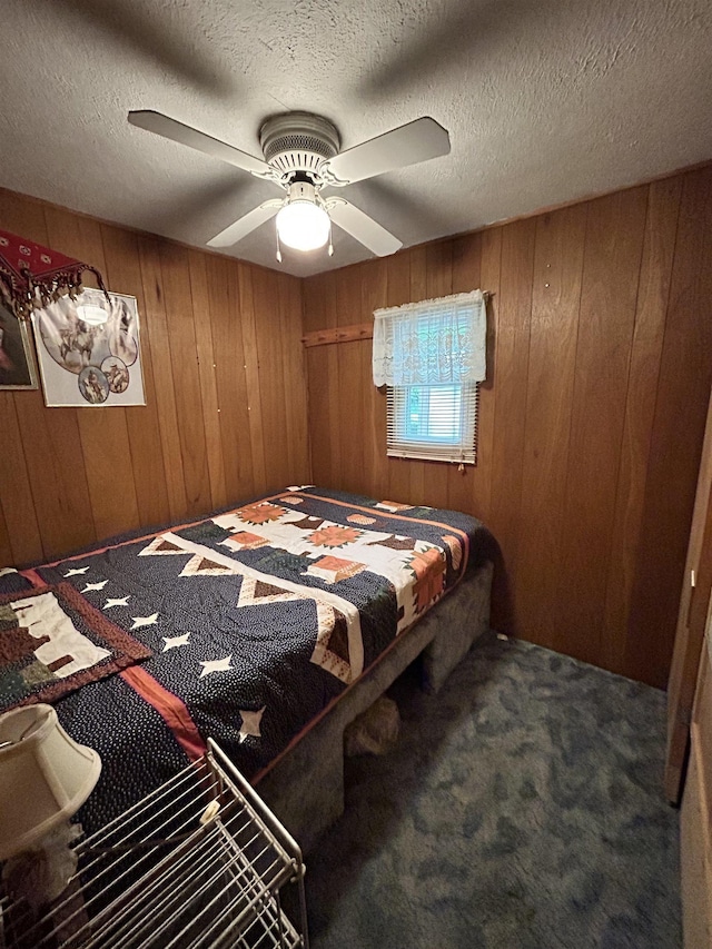 carpeted bedroom with wooden walls, a textured ceiling, and ceiling fan