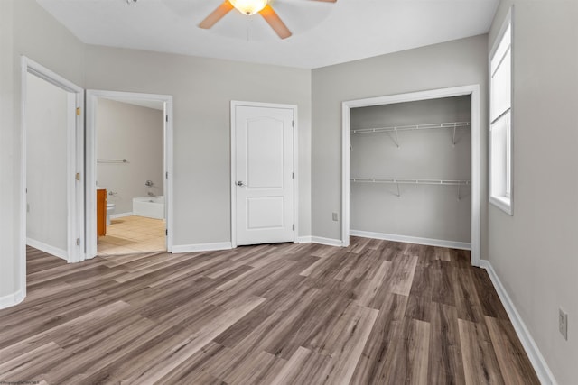 unfurnished bedroom featuring hardwood / wood-style flooring, ceiling fan, ensuite bath, and a closet