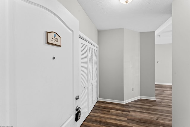 corridor featuring dark wood-type flooring and a textured ceiling