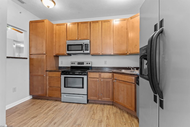 kitchen featuring stainless steel appliances, sink, a textured ceiling, and light hardwood / wood-style floors