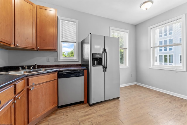 kitchen with appliances with stainless steel finishes, sink, and light hardwood / wood-style flooring