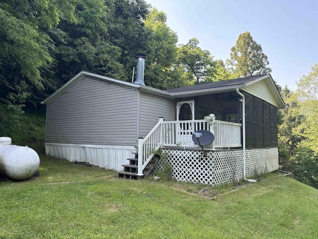 rear view of house featuring a sunroom and a yard