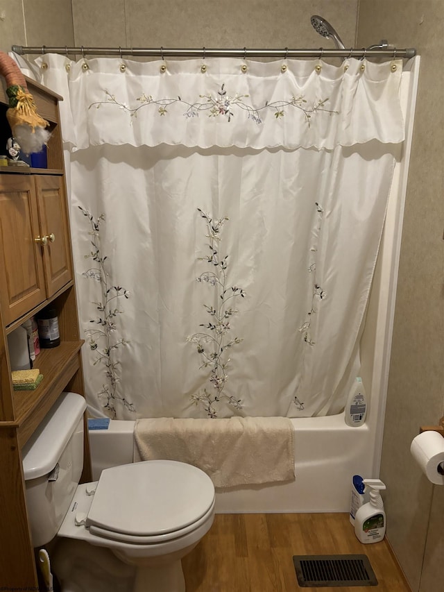 bathroom with wood-type flooring, shower / tub combo, and toilet