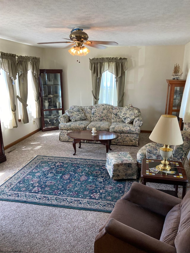 living room with ceiling fan, a textured ceiling, and carpet floors