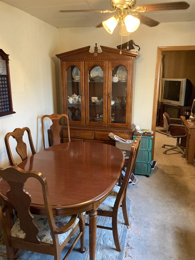 dining area with ceiling fan and light colored carpet