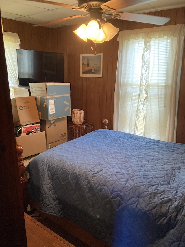 bedroom with ceiling fan and wood walls