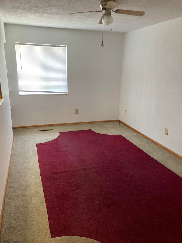 spare room with a textured ceiling, ceiling fan, and carpet floors