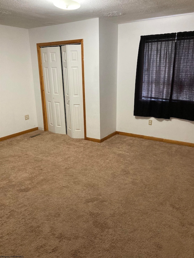 unfurnished bedroom with a textured ceiling, a closet, and carpet