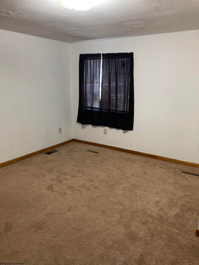 empty room featuring a textured ceiling and carpet