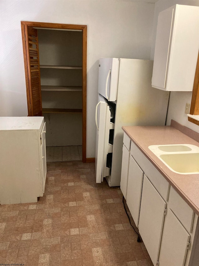 kitchen with sink, white cabinets, and light tile floors