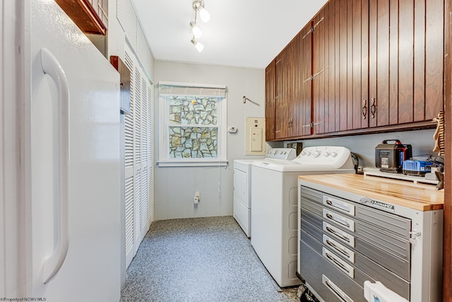 washroom featuring wooden walls, separate washer and dryer, cabinets, and rail lighting