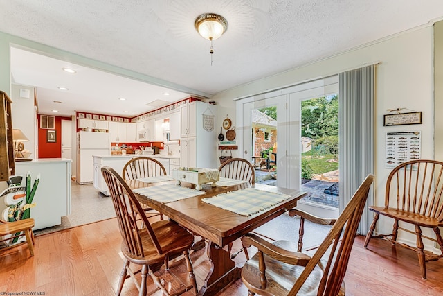 dining room featuring light hardwood / wood-style floors, a textured ceiling, and french doors