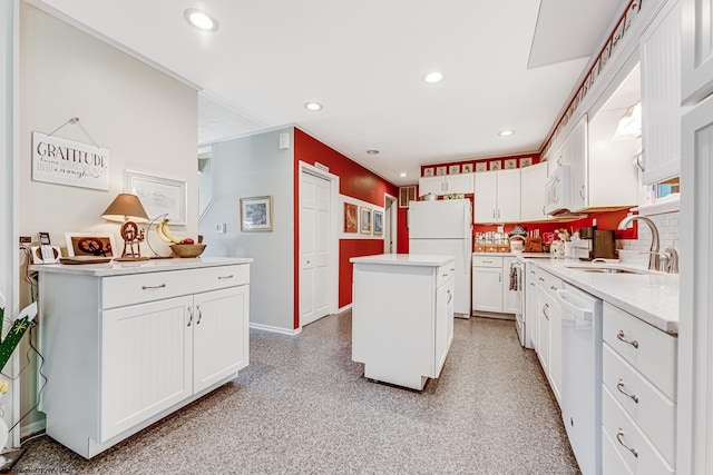 kitchen with backsplash, a center island, white cabinets, sink, and white appliances