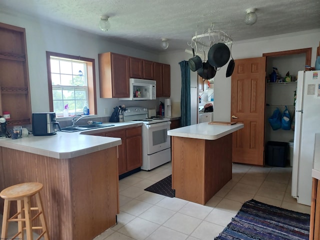 kitchen with white appliances, sink, light tile patterned floors, a textured ceiling, and kitchen peninsula