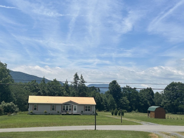 single story home featuring a mountain view, a front lawn, and a storage unit