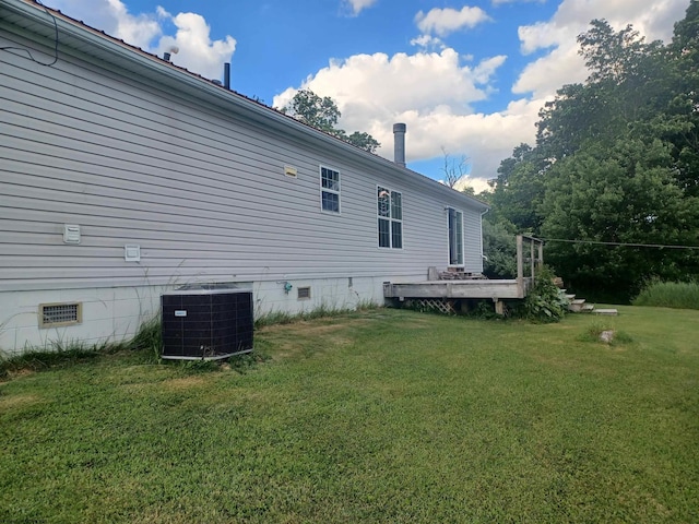 view of side of property featuring a yard and central AC