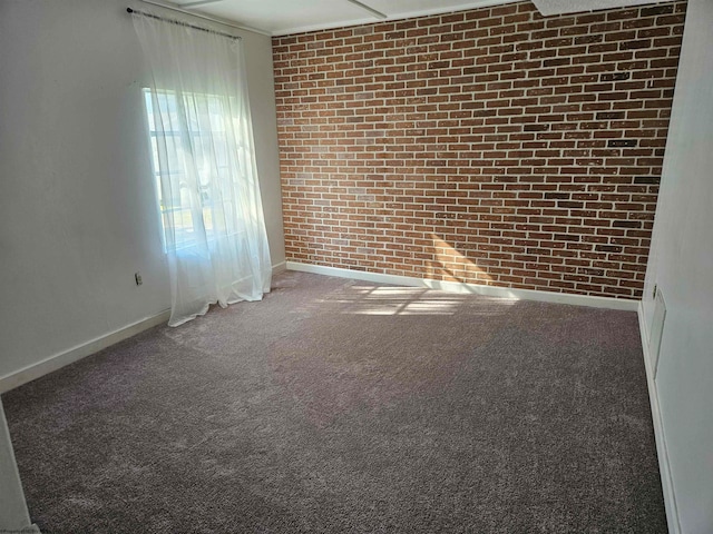 carpeted empty room featuring brick wall