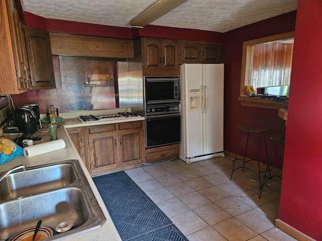 kitchen with light tile patterned flooring, black appliances, custom range hood, and sink