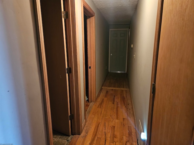 corridor featuring a textured ceiling and wood-type flooring