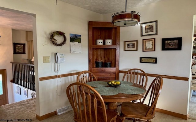 carpeted dining area with a textured ceiling