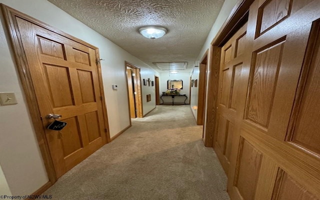 corridor with light carpet and a textured ceiling