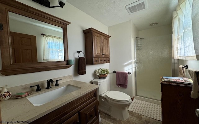 bathroom with an enclosed shower, vanity, a textured ceiling, and toilet