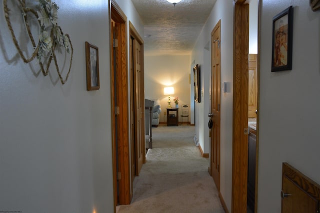 hall featuring light colored carpet and a textured ceiling