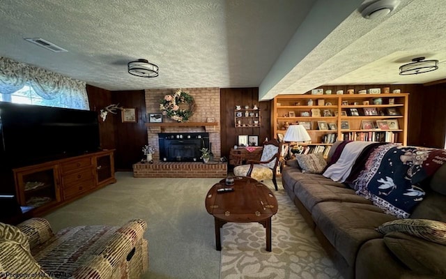 living room featuring carpet flooring, a textured ceiling, a fireplace, and wood walls