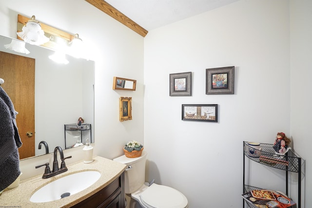 bathroom with vanity, beam ceiling, and toilet