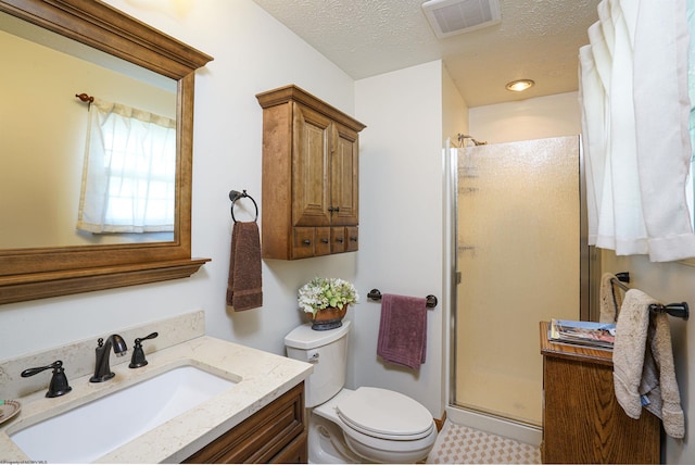 bathroom with a shower with door, vanity, a textured ceiling, and toilet