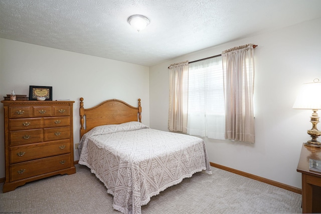 bedroom with light colored carpet and a textured ceiling