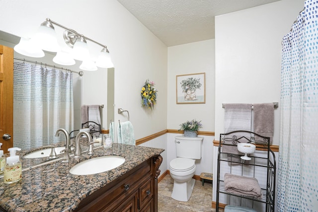 bathroom with vanity, toilet, and a textured ceiling