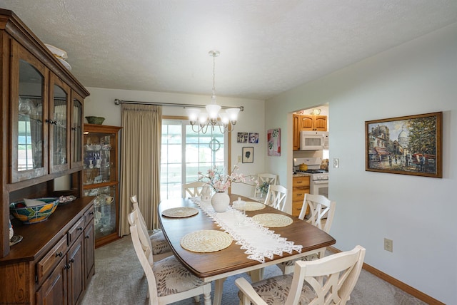 dining room with carpet, a textured ceiling, and an inviting chandelier