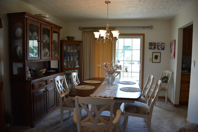 dining room featuring an inviting chandelier, carpet flooring, and a textured ceiling