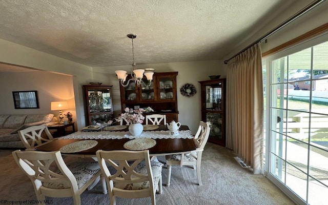 dining room with a chandelier, carpet floors, and a textured ceiling