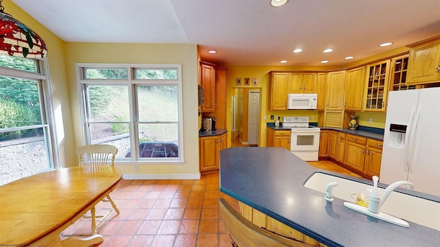 kitchen featuring white appliances, a healthy amount of sunlight, and light tile patterned flooring