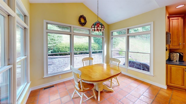 tiled dining room featuring a healthy amount of sunlight and vaulted ceiling