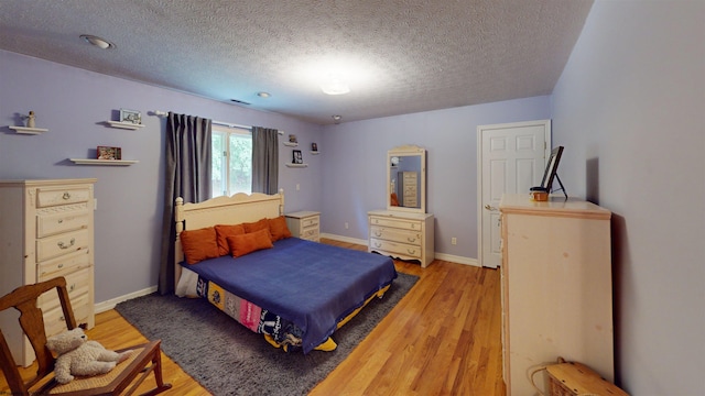 bedroom featuring a textured ceiling and light hardwood / wood-style flooring