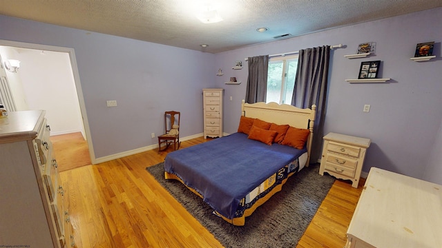 bedroom featuring a textured ceiling and light hardwood / wood-style flooring