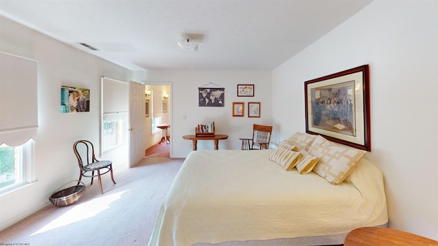 bedroom featuring ensuite bathroom and light colored carpet